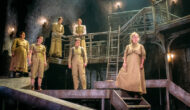 The asylum patients stand on the set, on multiple different levels, they are all looking at something opposite them.