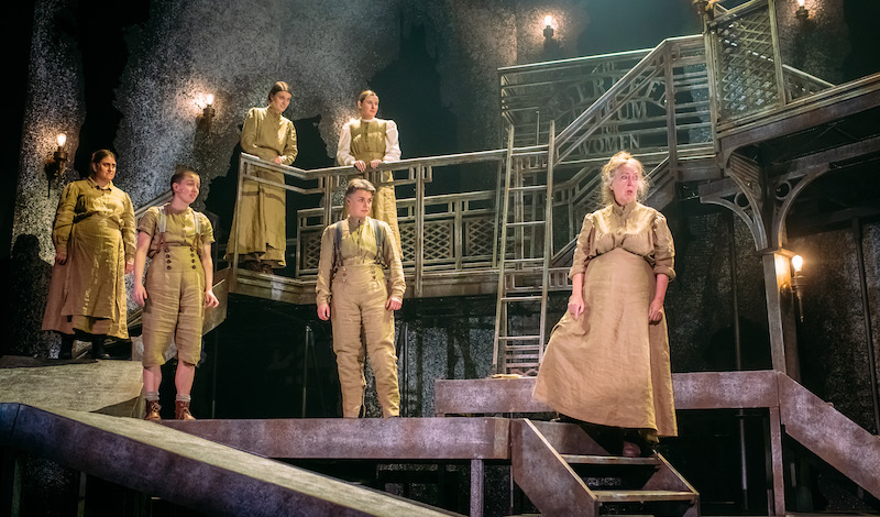 The asylum patients stand on the set, on multiple different levels, they are all looking at something opposite them.