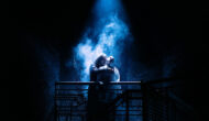 A dark stage with an eerie blue light illuminating Dracula as they prepare to feast on a lifeless Lucy.