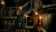 Jonathan and Dracula shake hands with their arms outstretched from their bodies as far as possible.
