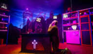 A man is on his knees praying. He is in a holy place, with marble statues, crosses and neon lights.